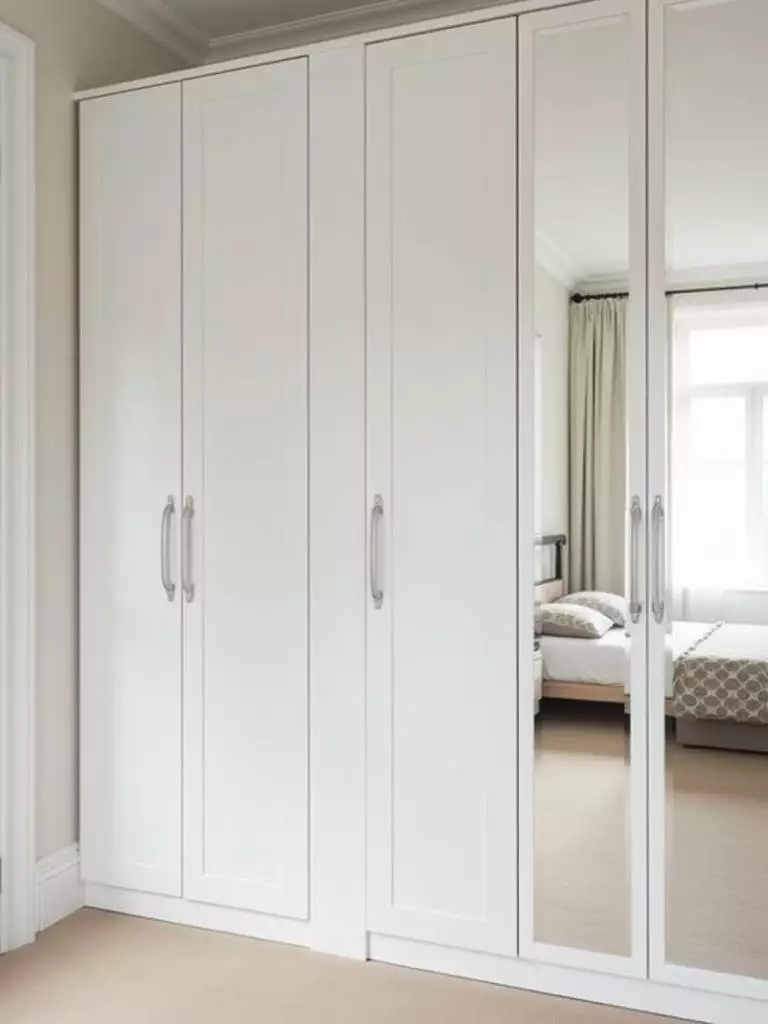 Small bedroom featuring a white wardrobe with full-length vertical mirrors, enhancing functionality and creating spaciousness.