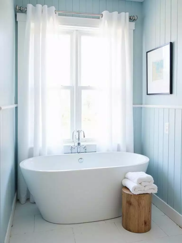 Coastal bathroom with white freestanding tub and light blue shiplap walls