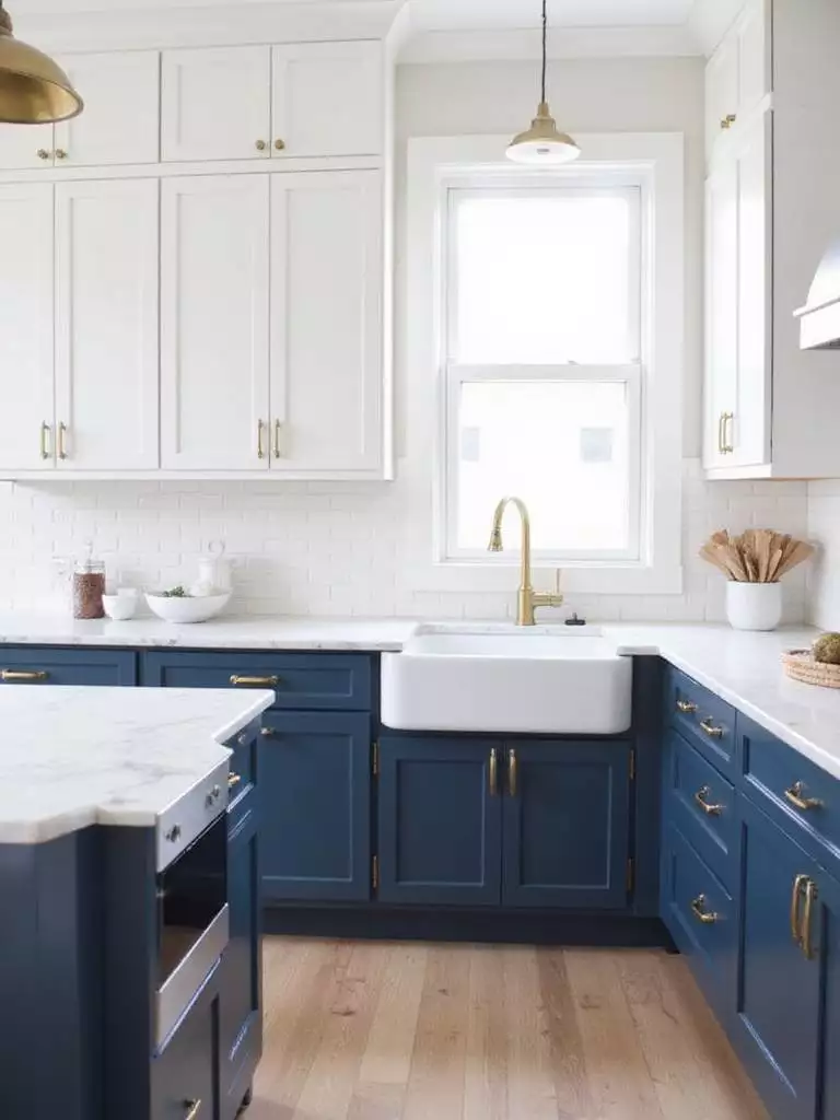 Classic blue and white kitchen with shaker cabinets, marble countertops, and brass hardware
