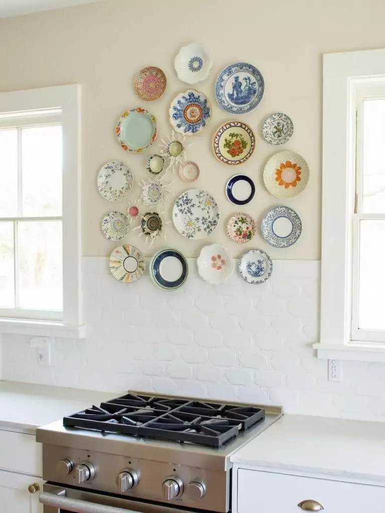 Eclectic gallery wall of decorative plates above a stove in a modern kitchen.
