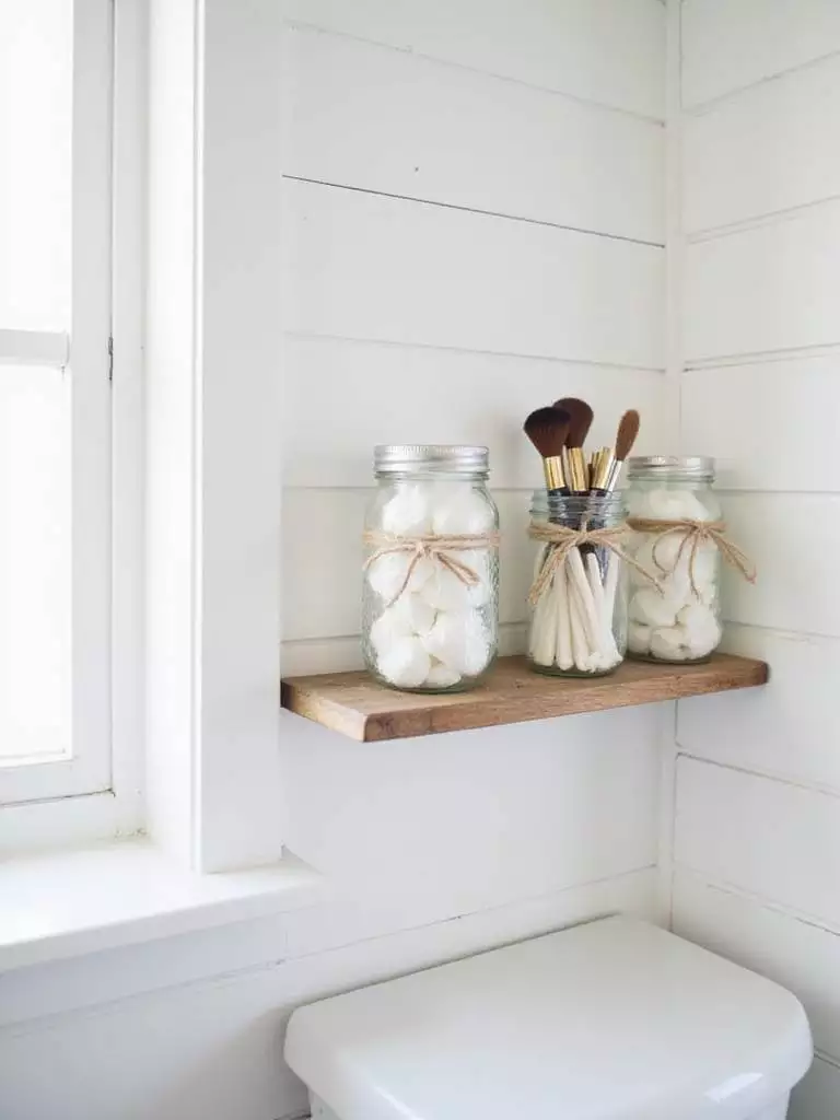 Farmhouse bathroom with mason jar organizers on a reclaimed wood shelf