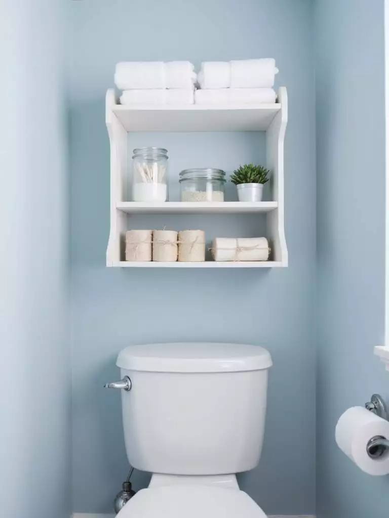 Over-toilet shelf in a small bathroom maximizes storage and adds style.