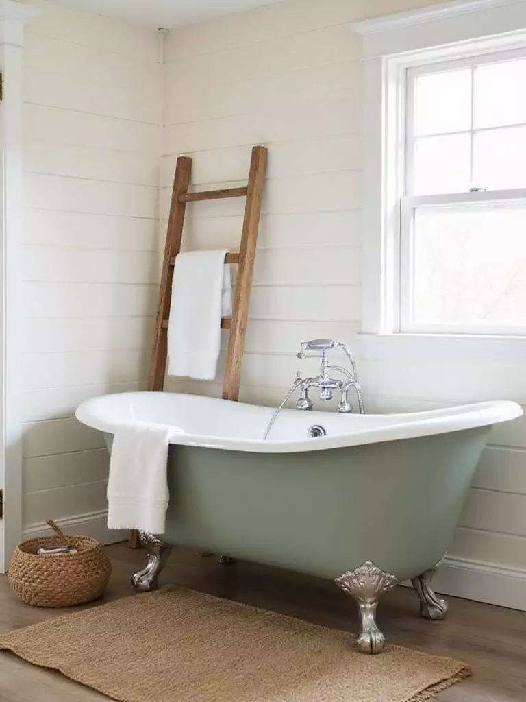 Rustic bathroom featuring a sage green clawfoot tub and shiplap walls.