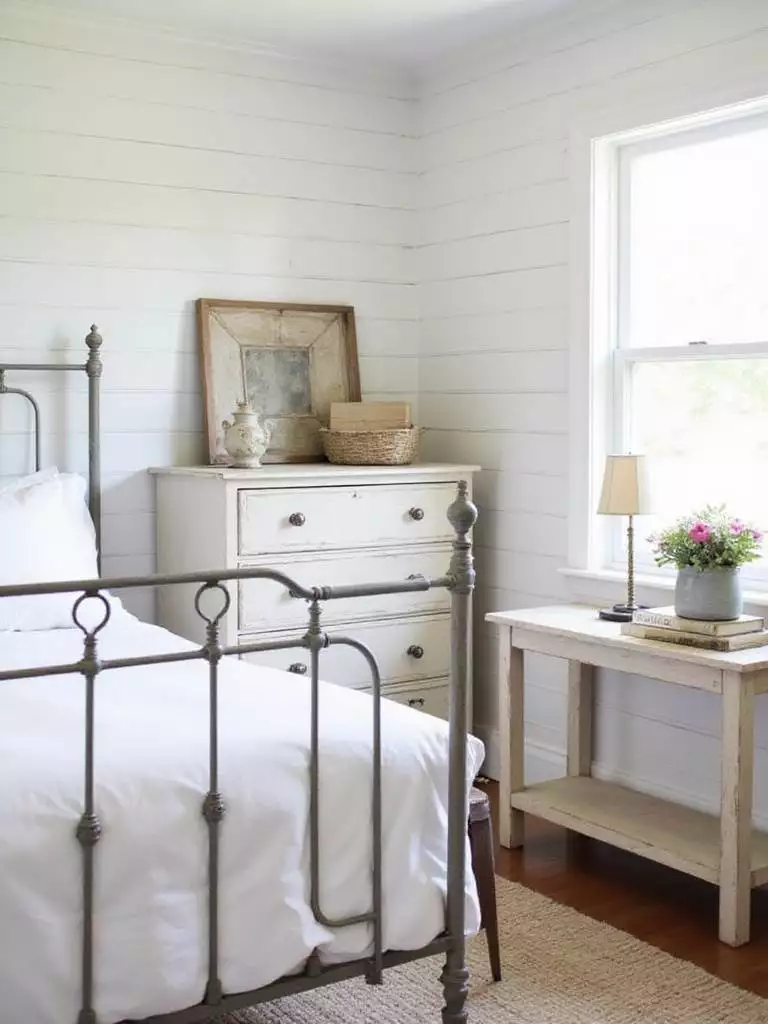 Farmhouse bedroom with vintage iron bed and distressed wooden dresser
