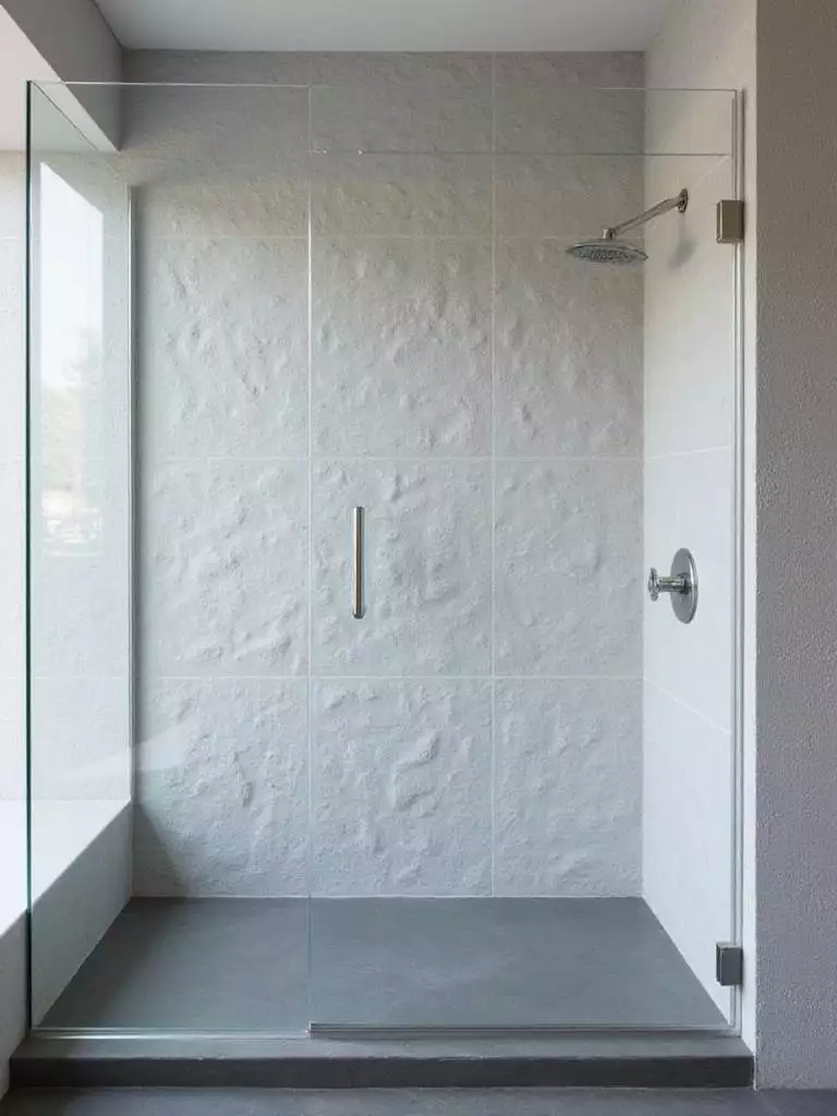Modern shower with textured geometric tile wall in light gray