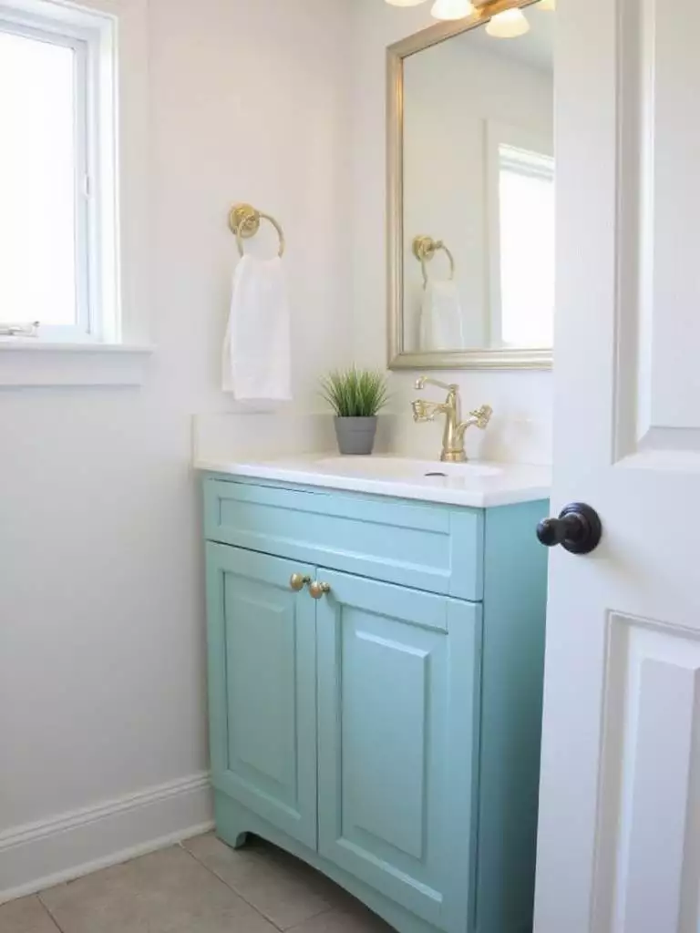 Bathroom vanity with teal paint and brushed gold hardware