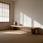 A serene apartment living room designed in Shibumi style, featuring a minimalist unfinished wooden bench, hand-thrown ceramic vase, natural fiber mat, and soft diffused natural light, emphasizing thoughtful restraint and spaciousness.