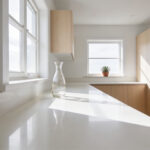 A bright and decluttered minimalist small kitchen with light wood cabinets and empty white countertops under soft natural light.